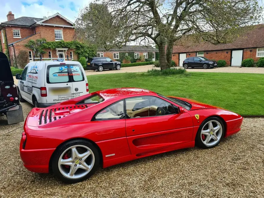 Side view of a red Ferrari F355 on a gravel drive after a valet, with the WL Mobile Valeting van behind.