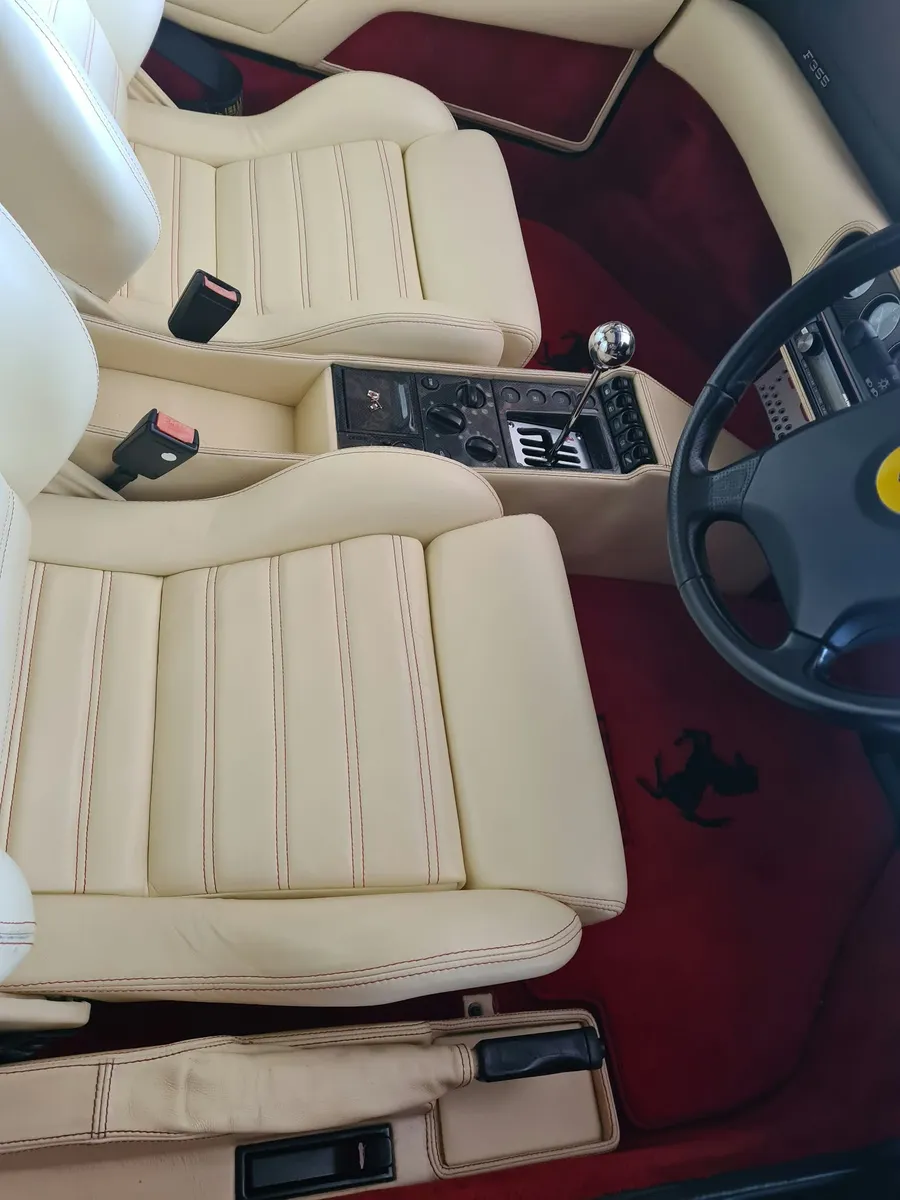 The cream leather seats and red carpets of a Ferrari F355 after an interior valet.
