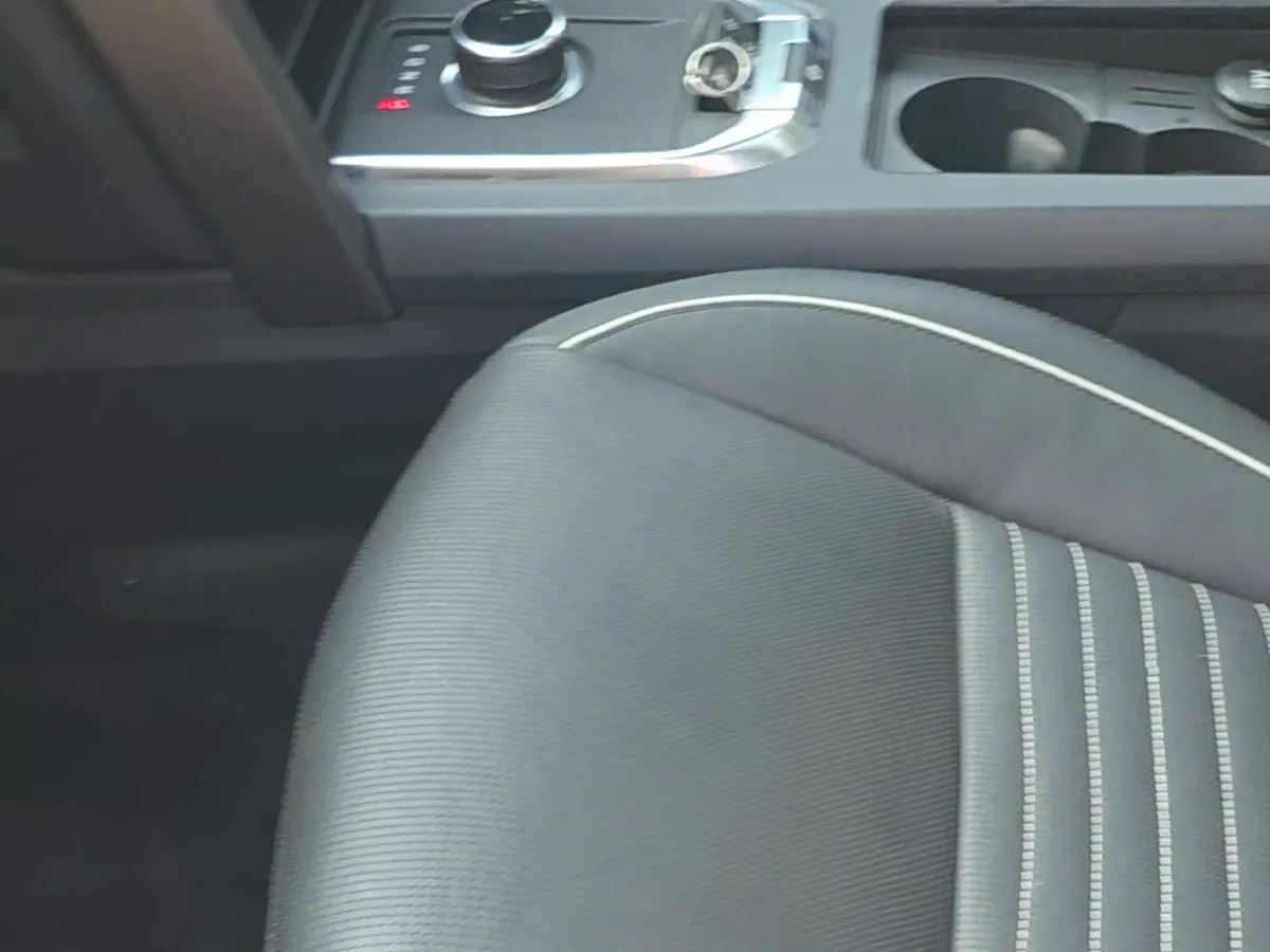 A cleaned black leather front seat with white piping next to the centre console.