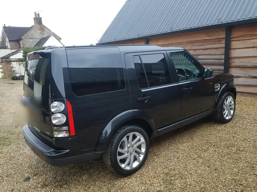 Rear three-quarter view of a black Land Rover Discovery on gravel after an exterior valet.
