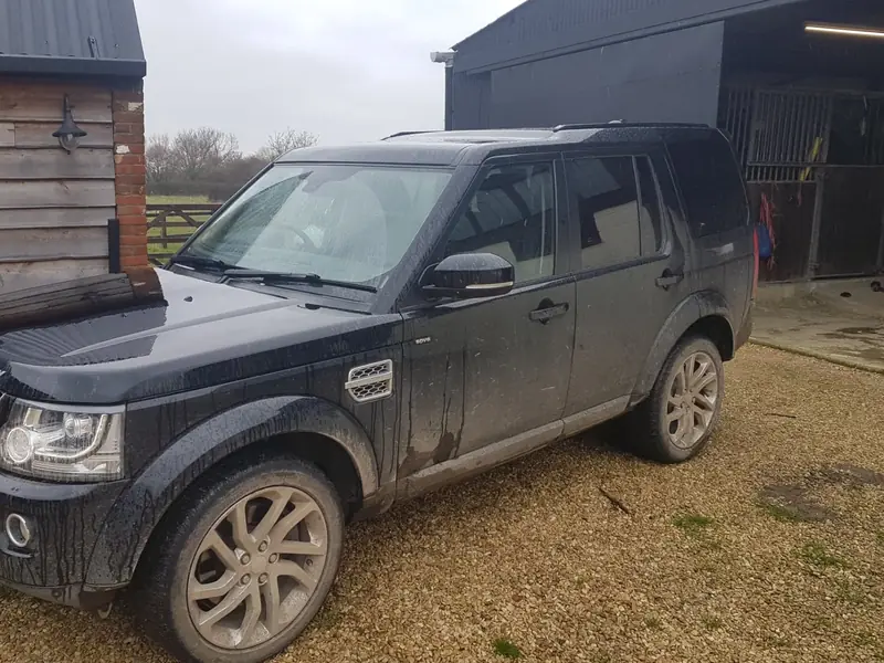 Black Land Rover Discovery 4 covered in mud up the doors and wheels