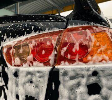 Rear light of a black car covered in soap from a mobile valeting service