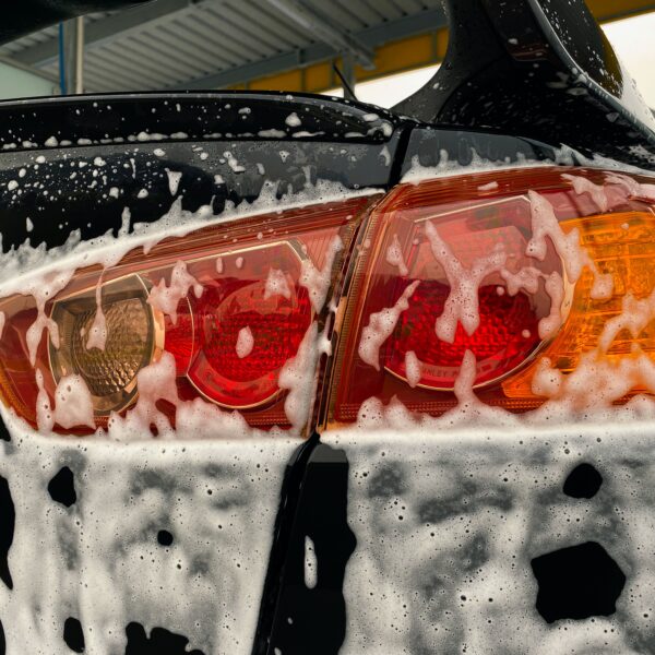 Rear light of a black car covered in soap from a mobile valeting service