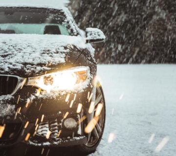 A black car in the snow showing the importance of ceramic coating your car for winter.