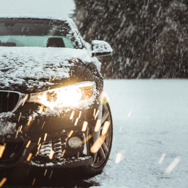 A black car in the snow showing the importance of ceramic coating your car for winter.