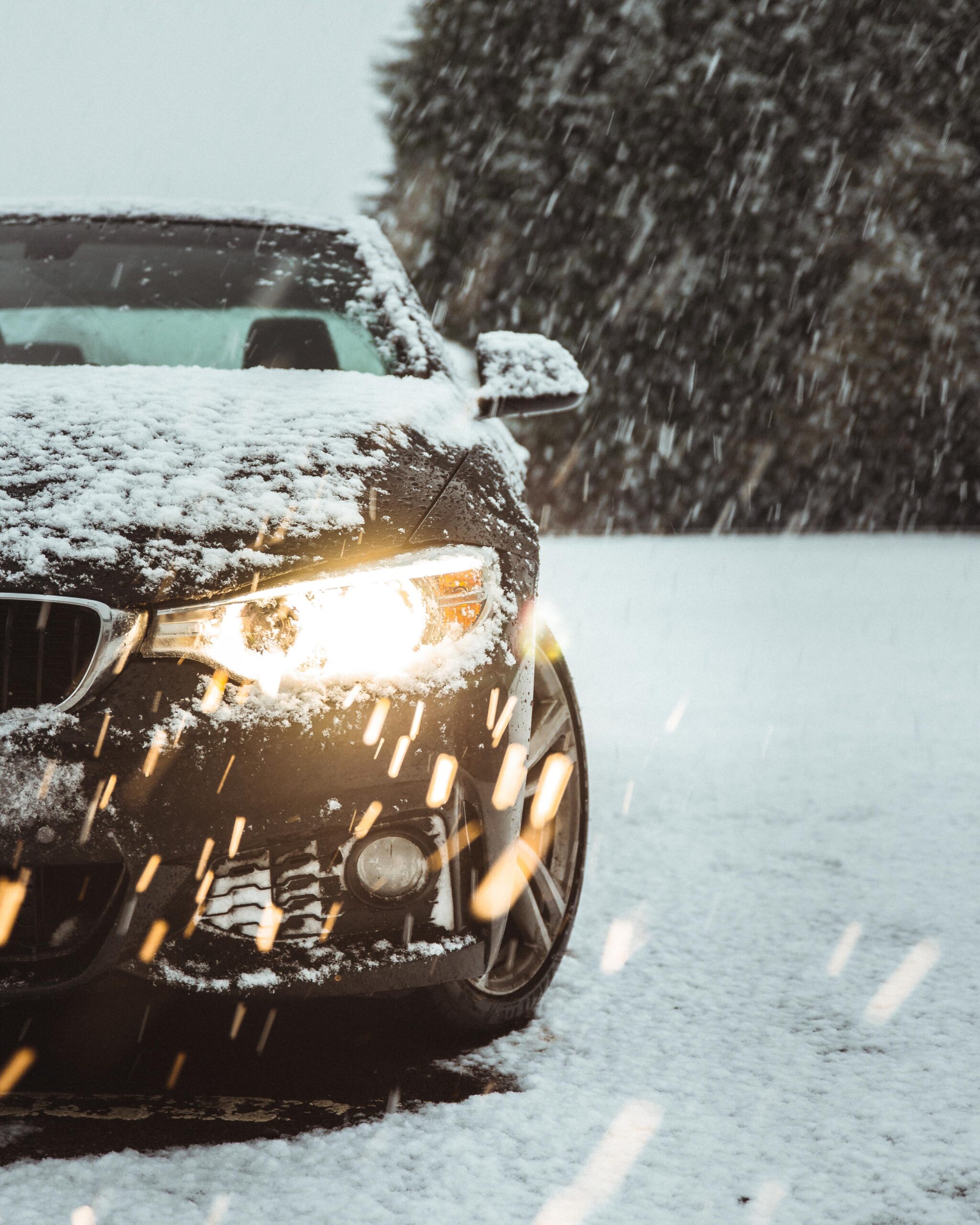 A black car in the snow showing the importance of ceramic coating your car for winter.