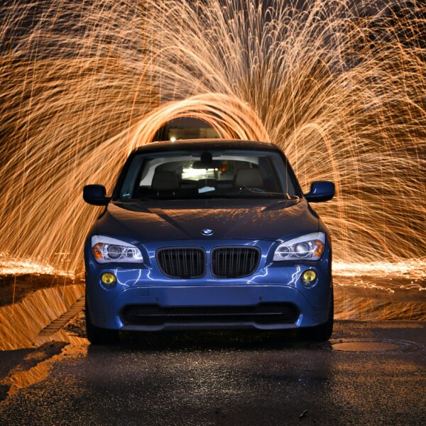 A blue car illuminated from behind by a spinning firework. Celebrating the New Year and time for a new car washing routine.